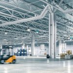 Wide-angle view of a spacious, well-lit warehouse with forklift in motion blur. 3d render