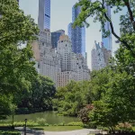 New York City, USA – June 16, 2026: Central Park Pond framed by green trees and Midtown Manhattan skyscrapers.