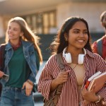 Happy Indian student going on a lecture at the university. Her friends are in the background.