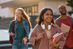 Happy Indian student going on a lecture at the university. Her friends are in the background.