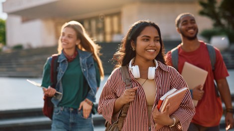 Happy Indian student going on a lecture at the university. Her friends are in the background.