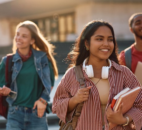 Happy Indian student going on a lecture at the university. Her friends are in the background.